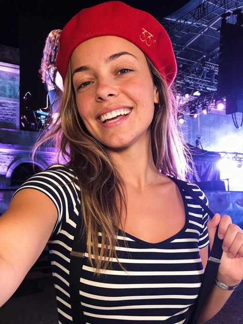 Mia sourit avec un béret rouge lors d’un concert